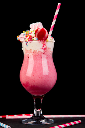 Pink Extreme milkshake with berry, rasberry, strawberry, candy marshmallow, lollipops on black background.. Crazy freakshake. Copy space. Food trend Overshakeの写真素材