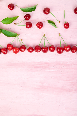 Ripe cherry berries and cherry  leaf colourful bright pattern on pink background. Top view. Flat lay.の写真素材