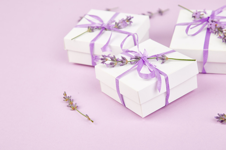 White Gift box with violet ribbon and bouquet of flower lavender on pink background. Celebration, birthday. Decoration present. Copy space.の写真素材