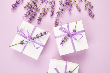 White Gift box with violet ribbon and bouquet of flower lavender on pink background. Celebration, birthday. Decoration present. Flat lay. Copy space.の写真素材