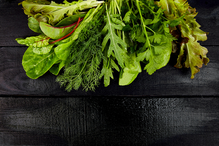 Mix leaf salad on black table. Flat lay. Copy space. Lettuce, mangold, parsley, dill, arugula Healthy diet Clear food Veganの写真素材