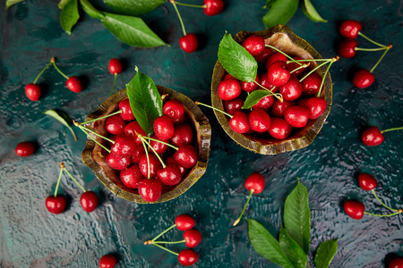 Red cherry in bowl on green background. Summer or spring concept. Harvest. Top view. Flat layの写真素材