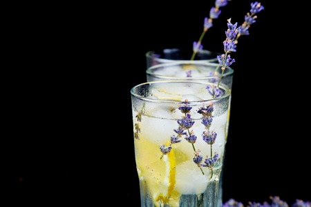Lavender lemonade with lemon and ice on black background. Detox water. Summer drink. Diet cocktail. Beautiful.の写真素材