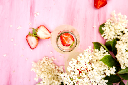 Kombucha tea with elderberry  flower and strawberry on pink background. Homemade fermented infused drink . Summer Healthy natural probiotic flavored drink. Copy space. Top view.の写真素材