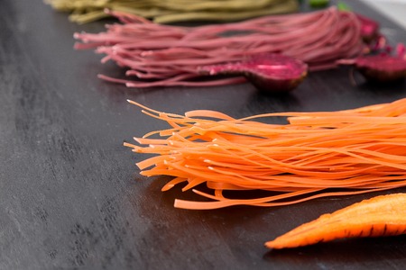 Colored Raw Vegetable Vegetarian Pasta with Beets, Carrots and Spinach. Copy space. Close up.の写真素材