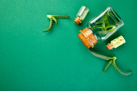 Aloe vera oil in glass bottle and towel for spa on green background. Star cactus, Aloin, Jafferabad, Aloe barbadensis, Barbados herbal medicine for skin treatment and care. Top view, flat layの写真素材