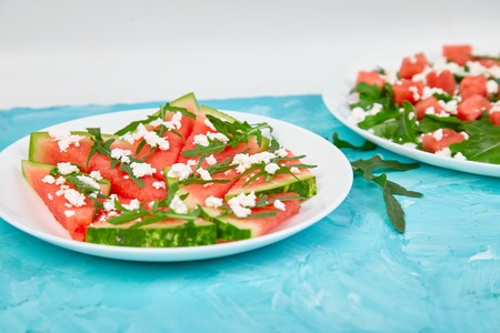 Fresh summer watermelon salad with feta cheese and arugula on blue table background. Vegan food. Diet, Vegetarian. Copy spaceの写真素材