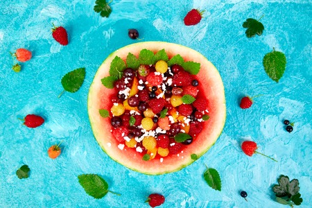 Watermelon bowl with cottage cheese and berries, apricot, raspberry, gooseberries.
Healthy summer breakfast concept, fruit salad in carved watermelon. Vegan food. Still life. Copy space. Flat layの写真素材