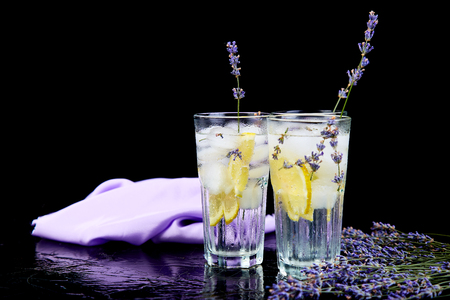 Lavender lemonade with lemon and ice on black background. Detox water. Summer drink. Diet cocktail. Beautiful.の写真素材