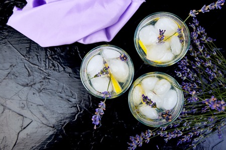 Lavender lemonade with lemon and ice on black background. Detox water. Summer drink. Diet cocktail. Beautiful. Top view. Copy space.の写真素材