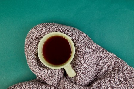 Knitted scarf with warm  cup of tea  on green background, Autumn. Fall season. Still life. Top view. Falt lay, Copy space,の写真素材