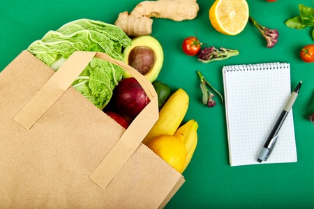 Shopping list, recipe book, diet plan. Grocering concept. Full paper bag of different fruits and...