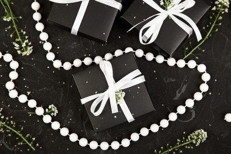 Wrapping modern Christmas or Birthday gifts presents. Gift boxes in Black and White color with flowers. Flat lay, top view. Beautiful.の写真素材