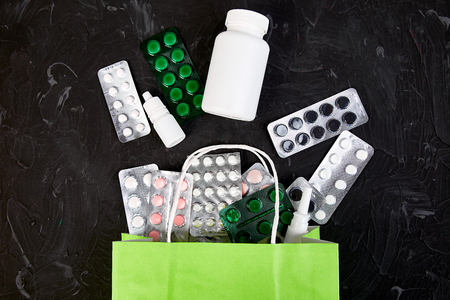 Shopping bag assorted medicine pills and blister on dark background. Creative idea.  Health marketplace concept. Flat lay.の写真素材