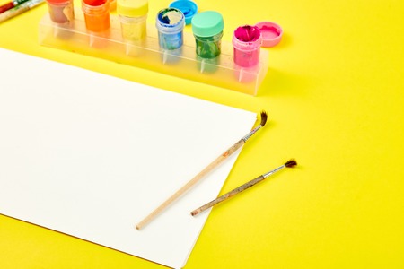 Watercolor palettes and paint brushes. Artist workplace on a yellow background. Minimal. Creative. Flat lay. Top view. Copy space.の写真素材