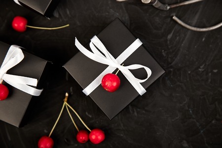 Wrapping modern Christmas or Birthday gifts presents. Gift boxes in Black and White color with red little apples. Flat lay, top view. Beautifulの写真素材