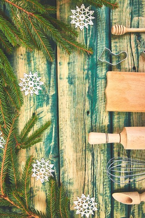 Christmas cooking or baking food background with kitchen utensils, rolling pin, cutting board, spoon, fir branches and holiday decoration on green wooden rustic background. Top view. Flat lay. Copy space.の写真素材