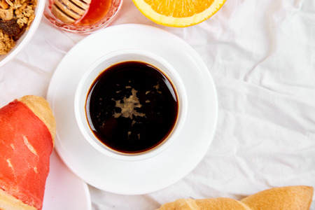 Good morning. Continental breakfast on white bed sheets. Cup of coffee, orange juice, croissants, jam muesli, granola, from above. Top view. Flat lay. Copy spaceの写真素材