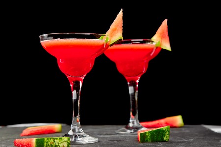 Watermelon margarita cocktail on black background. Fresh watermelon lemonade with mint and  ice for summer party. Refreshing summer drink.の写真素材