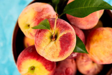 Ripe peaches in a bowl, basket on the blue table. Copy space. Flat lay. Top view.の写真素材
