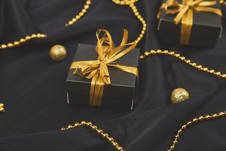 Luxury black gift boxes with gold ribbon on shine