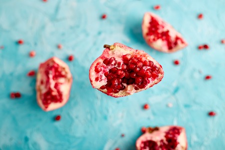 Half pomegranate fruit on blue background. Fresh red ripe pomegranate and seeds  Free space for text . Overhead. Top viewの写真素材