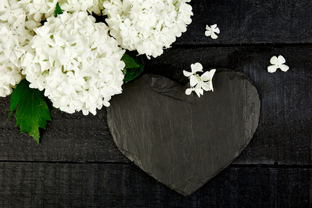 Valentine Day Bouquet flower hydrangea and slate heart on black wooden background. Good morning. Flat lay. Top view. Love.の写真素材