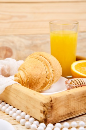 Continental breakfast on ristic wooden background. Orange juice, croissants, jam on wooden trayの写真素材