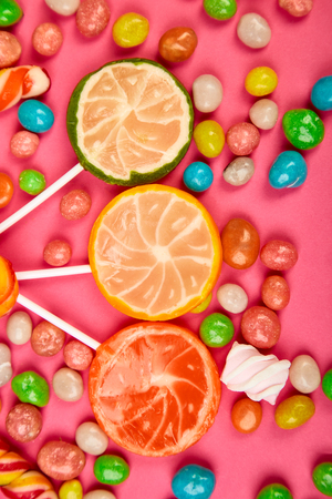 Colorful candy, jelly, lollipop on stick, scattering of multicolored sweets on pink background. Flat lay, Top view. Copy space.の写真素材