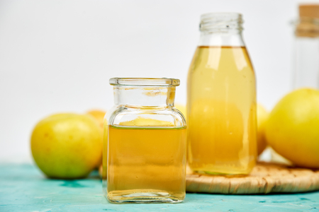 Glass Bottle of apple organic vinegar on blue background. Apple cider vinegar. 
Healthy organic drink food. Bottle of fresh cider near autumn yellow apples. Space for textの写真素材