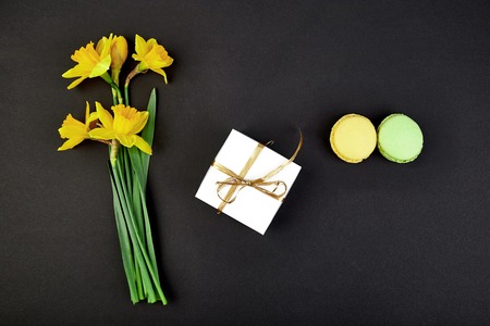 Bouquet flowers narcissus gift and sweets or cake macarons. Good morning. Woman or mother Day.Greeting conceptの写真素材