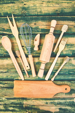 Cooking or baking food background with kitchen utensils, rolling pin, cutting board, spoon on green wooden rustic background. Top view. Flat lay. Copy space.の写真素材