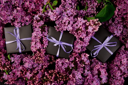 Black small gift boxes wrapped purple ribbon with natural lilac.