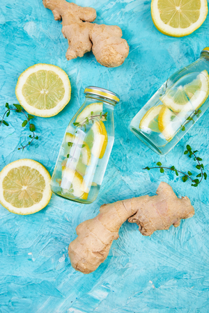 Trendy detox healthy drink. Detox water in bottles with ingredients, ginger, lemon, mint on blueの写真素材