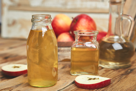 Apple cider vinegar. Glass Bottle of apple organic vinegar on wooden table.の写真素材