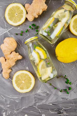 Trendy detox healthy drink. Detox water in bottles with ingredients, ginger, lemon, mint on grey background. Summer drink, lemonade. Diet. Flat lay. Top view. Copy space の写真素材
