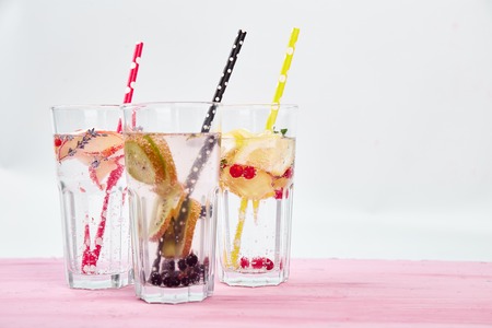 Variety of  Detox infused water with  kiwi, apple, lavender, ginger, lemon, mint on pink background. Refreshing summer homemade cocktail. Diet. Healthy drink. Copy space.の写真素材