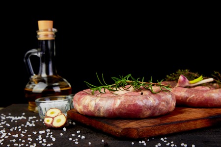 Raw spiral pork sausages with rosemary, salt and peper on wooden cutting board.の写真素材