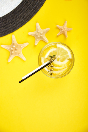 Holidays and drink concept. Cold cocktail, lemonade with lemon, mint  in a glass on a yellow table. Summer background. Detox water.の写真素材