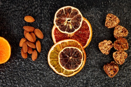 Healthy snacks -  variety oat granola bar,  rice crips, almond,  kiwi, dried orange, on black background. Mix assortment. Top view. Diet food. Gluten free Veganの写真素材