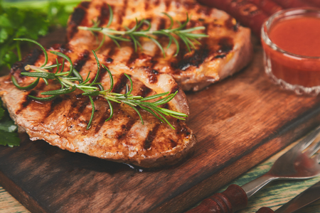 Grilled meat. Steak pork grill on wooden cutting board  on  rustic background  Top view. Flat lay.の写真素材