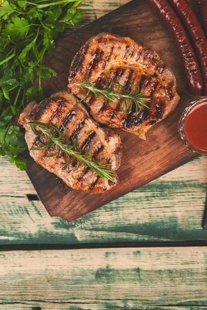 Grilled meat. Steak pork grill on wooden cutting board  on  rustic background  Top view. Flat lay.の写真素材