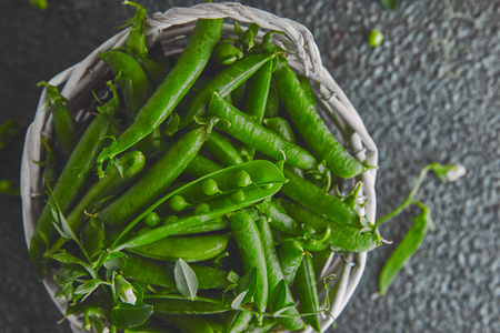 White Basket with fresh green peas on black background. Vegan and vegetarian food concept. Flat lay.の写真素材