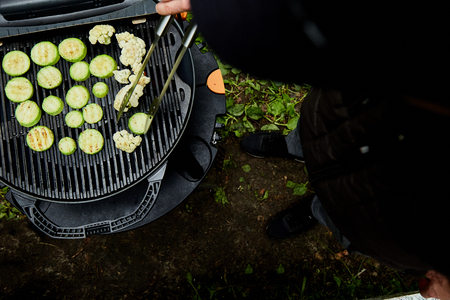 Hand of young man grilling zucchini vegetable on huge gas grill .の写真素材