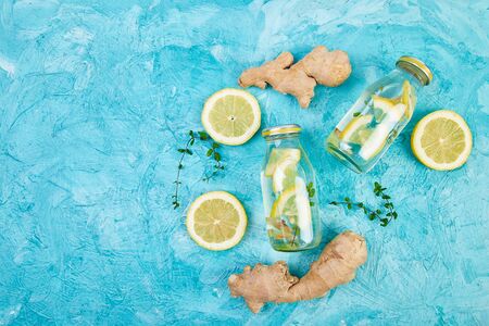 Trendy detox healthy drink. Detox water in bottles with ingredients, ginger, lemon, mint on blue background. Summer drink, lemonade. Diet. Flat lay. Top view. Copy space の写真素材