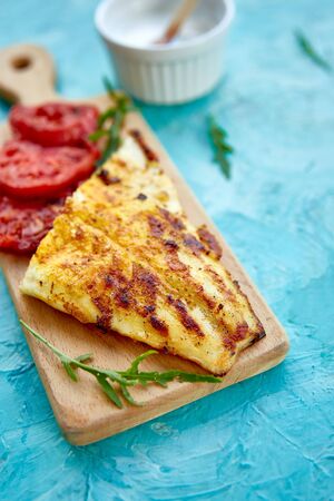 Grilled pike fillet with tomatoes on wooden board on blue background. Grilled seafood. Barbecue fish. Copy space. Healthy food.の写真素材