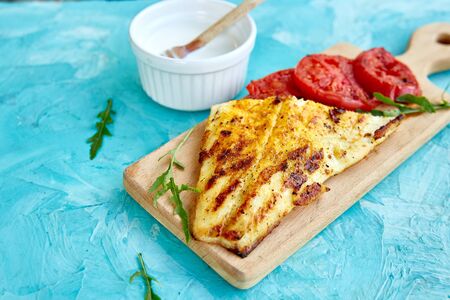 Grilled pike fillet with tomatoes on wooden board on blue background. Grilled seafood. Barbecue fish. Copy space. Healthy food.の写真素材