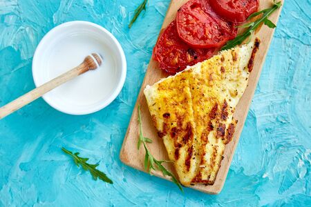 Grilled pike fillet with tomatoes on wooden board on blue background. Grilled seafood. Barbecue fish. Copy space. Healthy food.の写真素材