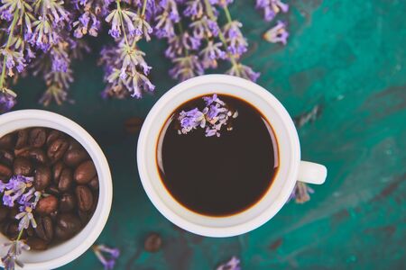 Coffee, coffee grain in cups and lavender flower on green background from above. Good Morning concept. Woman working desk. Cozy breakfast. Mockup. Flat lay styleの写真素材