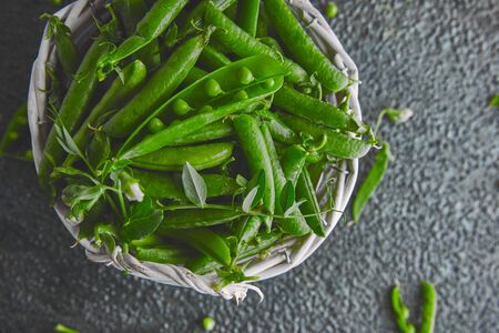 White Basket with fresh green peas on black background. Vegan and vegetarian food concept. Flat lay.の写真素材